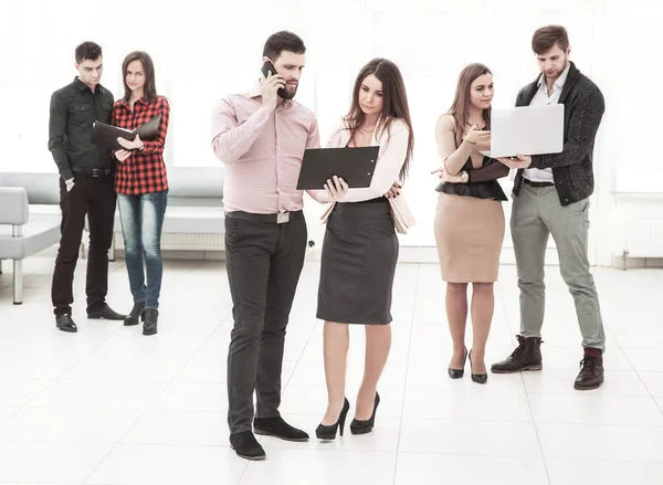 Equipo de negocios discutiendo documentos de pie en el vestíbulo de la oficina — Foto de Stock