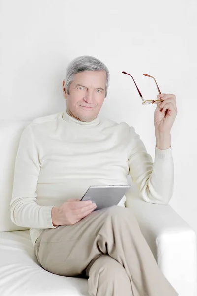 Äldre man med digitala tablett sitter i en stol. — Stockfoto