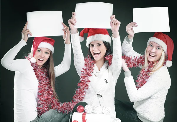 Três meninas no traje de Papai Noel mostrando folhas em branco — Fotografia de Stock