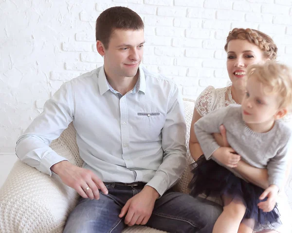 Familia feliz con la pequeña hija sentada en el sofá — Foto de Stock