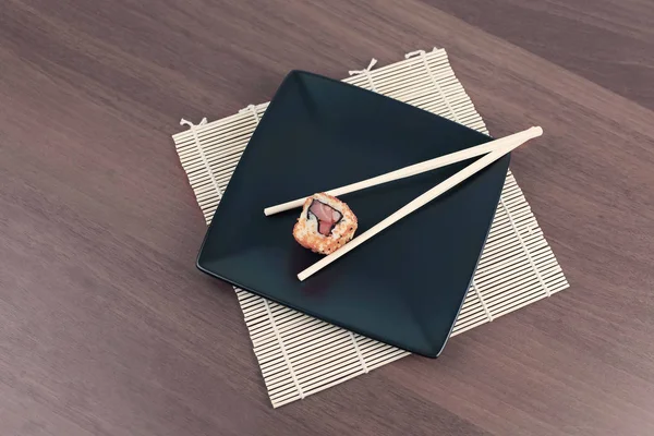 Suşi ve yemek çubuklarını ahşap bir masaya yakın plan çek.