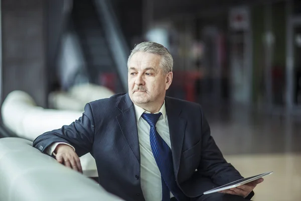 Portrait of businessman with digital tablet sitting in the chair in front of the office. — Stock Photo, Image