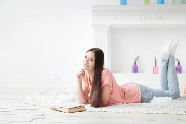 Porträt eines jungen Mädchens, das im Wohnzimmer auf dem Boden liegend Buch liest — Stockfoto