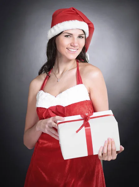 Pretty young woman dressed as Santa Claus holds Christmas gift — Stock Photo, Image