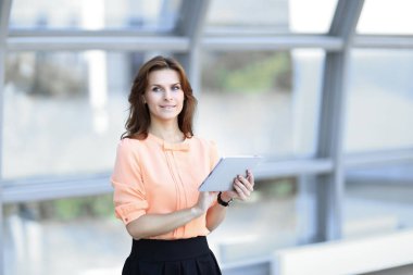 Kendine güvenen iş kadını bulanık office arka plan üzerinde dijital tablet ile.