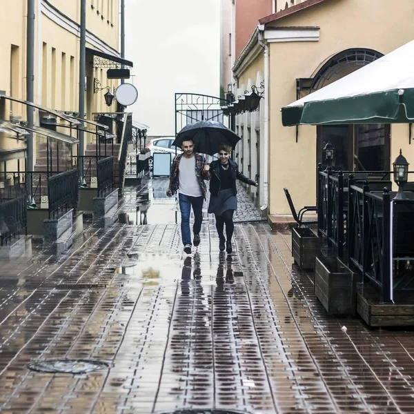 Pareja amorosa bajo un paraguas caminando por la calle de la ciudad vieja — Foto de Stock