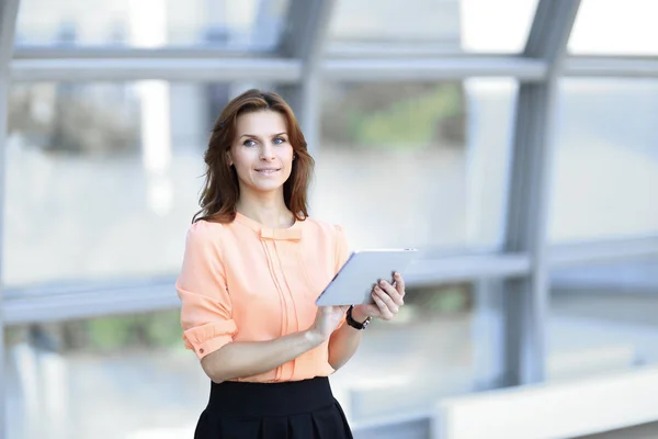 Confident business woman with digital tablet on blurred office background. — Stock Photo, Image