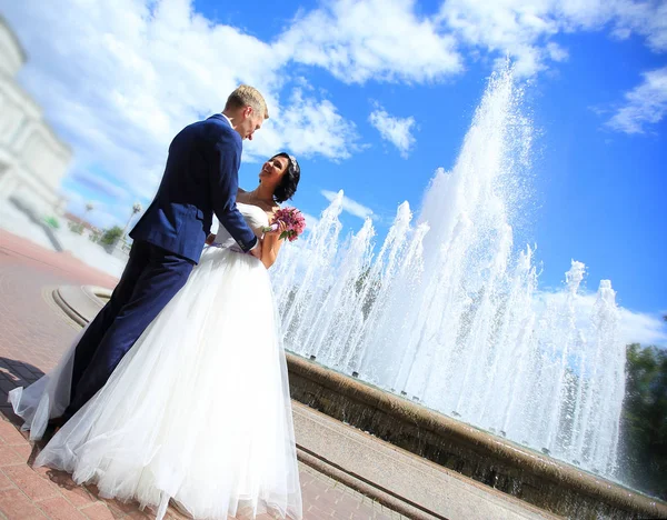 Любящие невеста и жених стоят рядом с фонтаном — стоковое фото