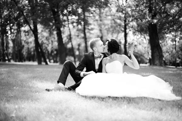 Portrait of happy groom and bride sitting in the lawn — Stock Photo, Image