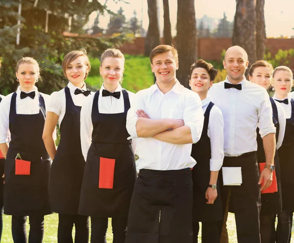 Grote groep koks en serveersters staan in een rij achter de chef-kok — Stockfoto
