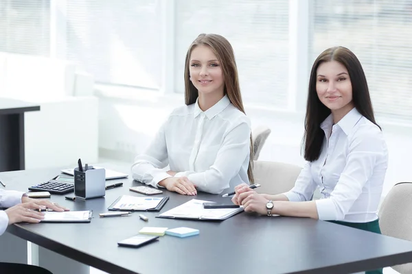 Tres jóvenes empleados sentados detrás de un escritorio — Foto de Stock