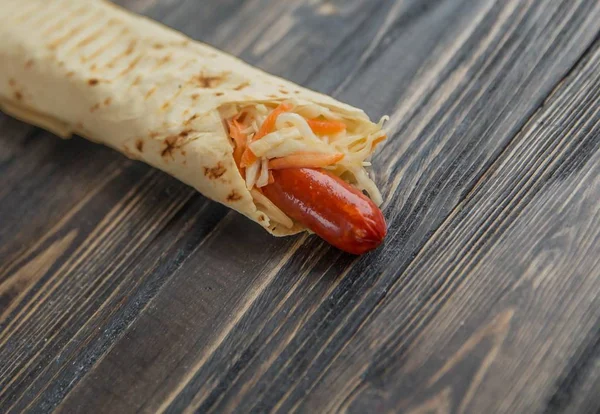 pork sausage and lettuce wrapped in pita bread on wooden background.photo with copy space