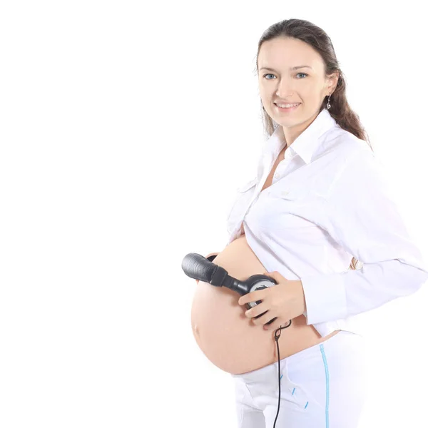 Mulher grávida feliz coloca fones de ouvido em sua barriga — Fotografia de Stock