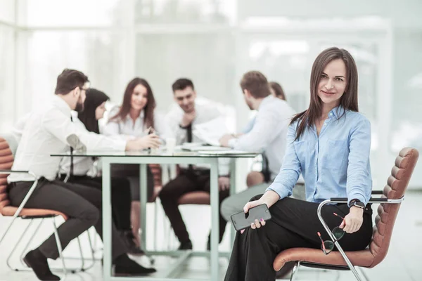 Ledande specialist på kvinnan sitter på kontorsstol på bakgrunden av business-team — Stockfoto
