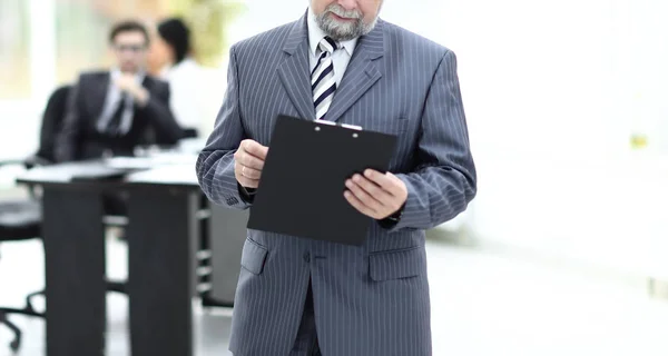 Hombre de negocios senior con portapapeles de pie en la oficina . — Foto de Stock