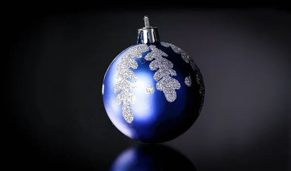 Bola de Natal azul brilhante em um fundo preto . — Fotografia de Stock