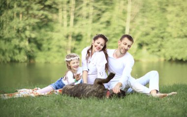 Güneşli bir yaz gününde piknikte köpekli mutlu bir aile. pregn