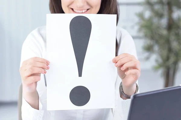 Business woman showing an exclamation mark sitting at the Desk — Stock Photo, Image