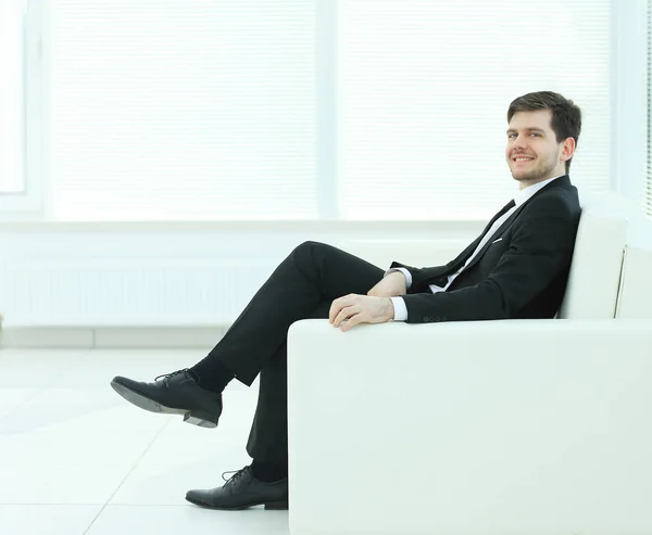 Biznesmenem, siedząc w fotelu na pakietu office z niewyraźne tło — Zdjęcie stockowe