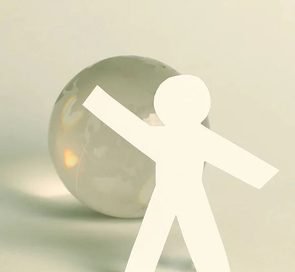 Paper man standing near the glass globe — Stock Photo, Image