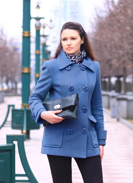 Beautiful girl in a purple coat in the Park with a clutch in her hands — Stock Photo, Image