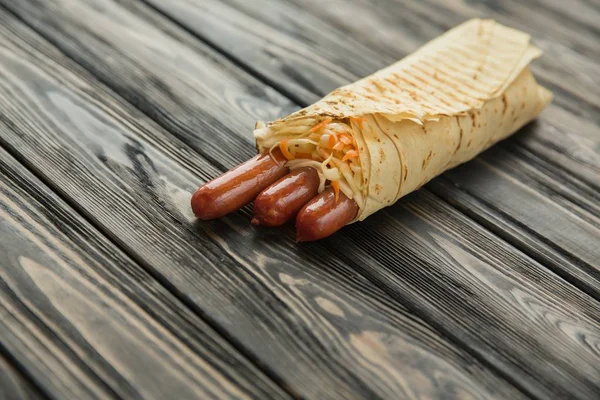 Spicy sausages in pita bread on wooden background — Stock Photo, Image