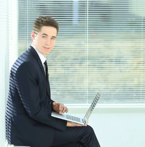 Jovem empregado trabalhando em um laptop sentado no corredor do th — Fotografia de Stock