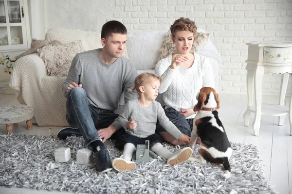 Padres con una hija pequeña y una mascota sentadas en el sofá . — Foto de Stock