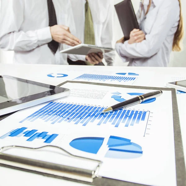 Digitális tábla és a pénzügyi diagramokat az asztalon, a háttérben a business Team — Stock Fotó