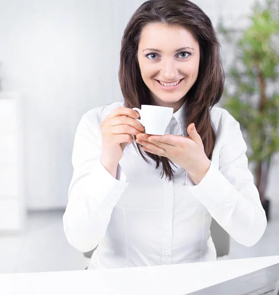 Successful business woman with coffee Cup sitting at her Desk — Stock Photo, Image