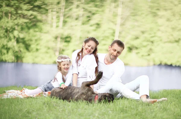 Szczęśliwa rodzina z psem na pikniku w słoneczny letni dzień. pregn. — Zdjęcie stockowe