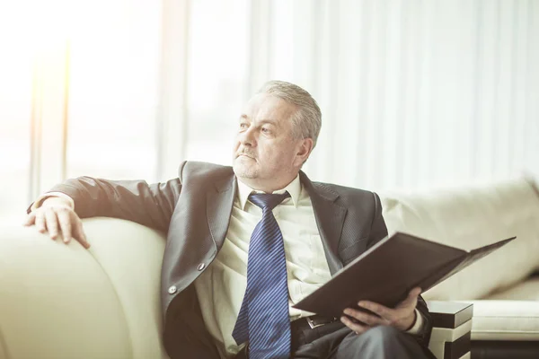 Successful businessman is considering a new contract sitting on the sofa in the private office — Stock Photo, Image