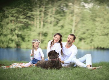 Güneşli bir yaz gününde piknikte köpekli mutlu bir aile. pregn