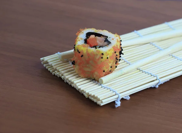 Sushi-Rollen und Essstäbchen auf Holzgrund. — Stockfoto