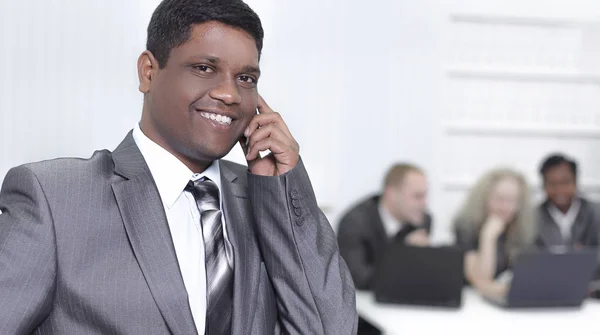 Foreground of a businessman talking on a mobile phone in the of — Stock Photo, Image