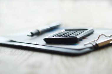 Kapat. Masaüstünde kalem ve hesap makinesinin bulanık görüntüsü