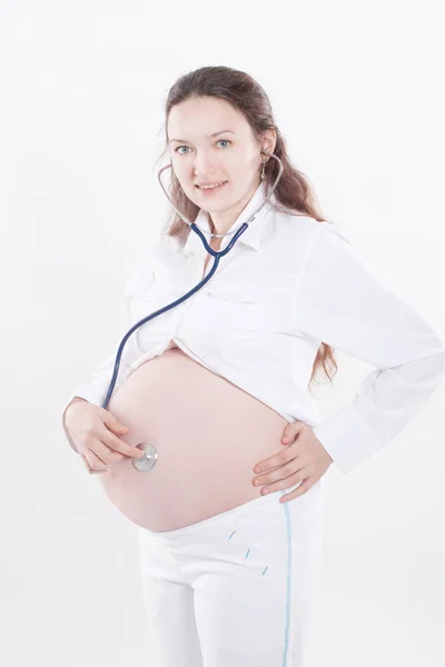 Pregnant woman listening through a stethoscope that makes her a child — Stock Photo, Image