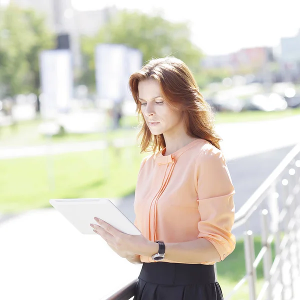 serious young woman with digital tablet on blurred city background