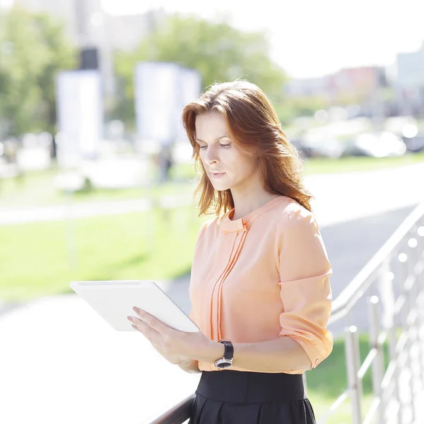 Serieuze jonge vrouw met digitale tablet op de achtergrond wazig stad — Stockfoto