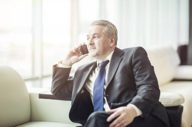 ofiste kanepede oturan onun smartphone cep telefonu ile konuşurken başarılı iş adamı