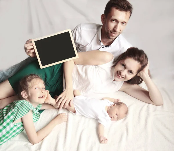 Feliz padre, madre y hermana mayor sosteniendo una tarjeta de cumpleaños fo — Foto de Stock