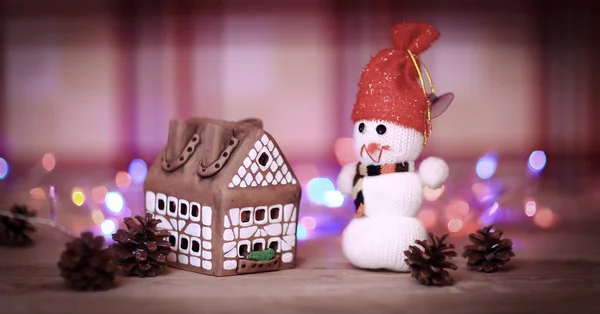 Speelgoed sneeuwpop en peperkoek huis aan de kersttafel — Stockfoto