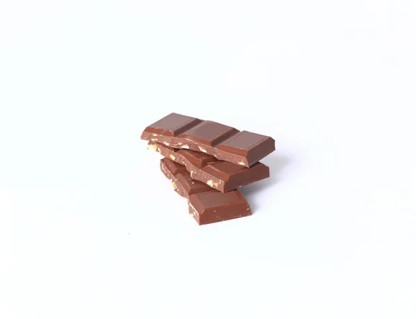 Stos kawałków czekolady z orzechami na białym tle — Zdjęcie stockowe