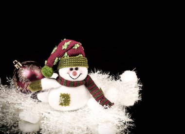 eğlenceli oyuncak kardan adam ve siyah bir arka plan üzerinde Noel topu.