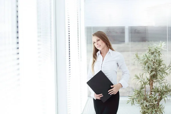 Framgångsrik affärskvinna med clipbord stående i ett modernt kontor — Stockfoto
