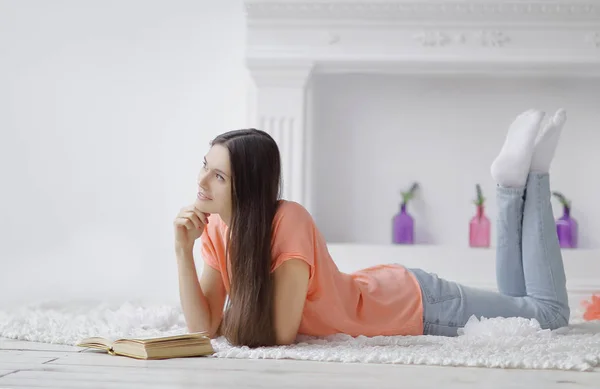 Retrato de niña leyendo libro tumbado en el suelo en la sala de estar — Foto de Stock