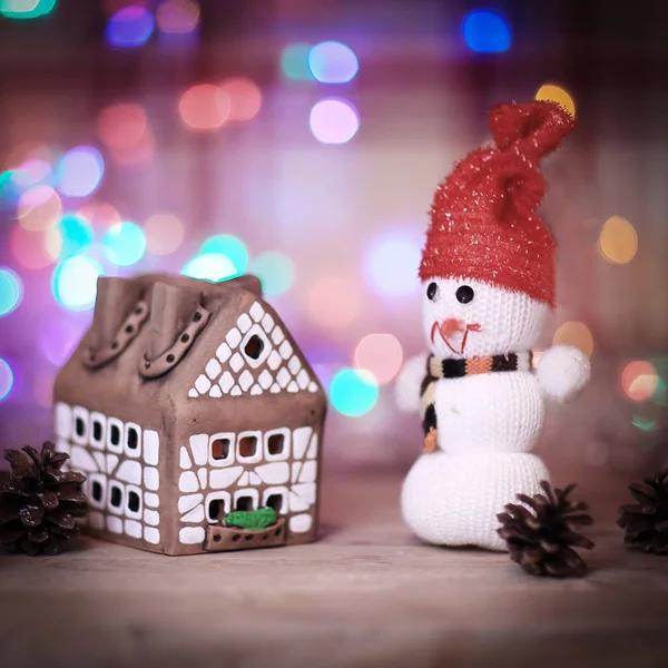 Speelgoed sneeuwpop en peperkoek huis aan de kersttafel — Stockfoto