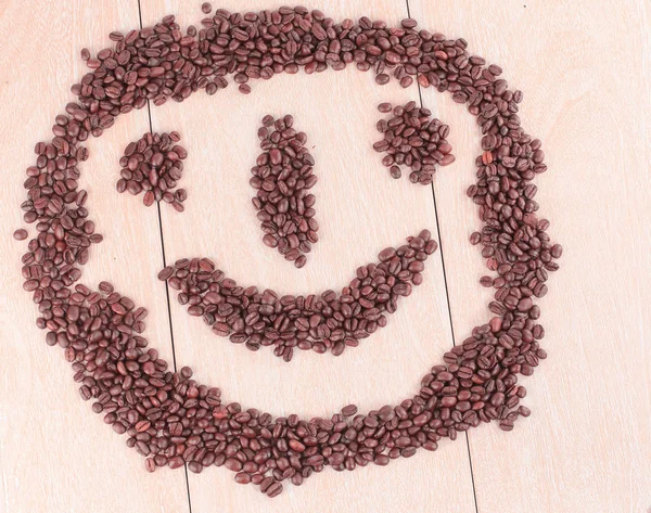 funny face of black coffee beans on wooden background