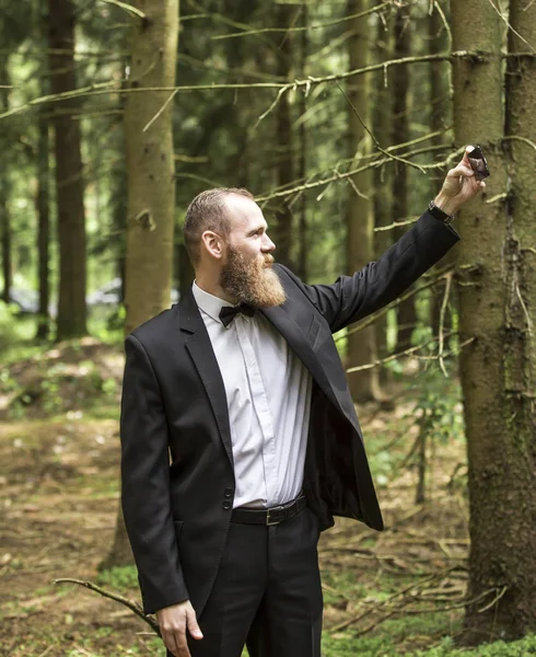 Мужчина в деловом костюме делает селфи на фоне соснового леса — стоковое фото