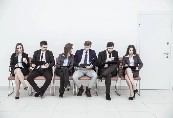 Equipo de negocios con documentos antes de la reunión de trabajo, sentado en sillas de oficina en el vestíbulo de la sala de conferencias — Foto de Stock